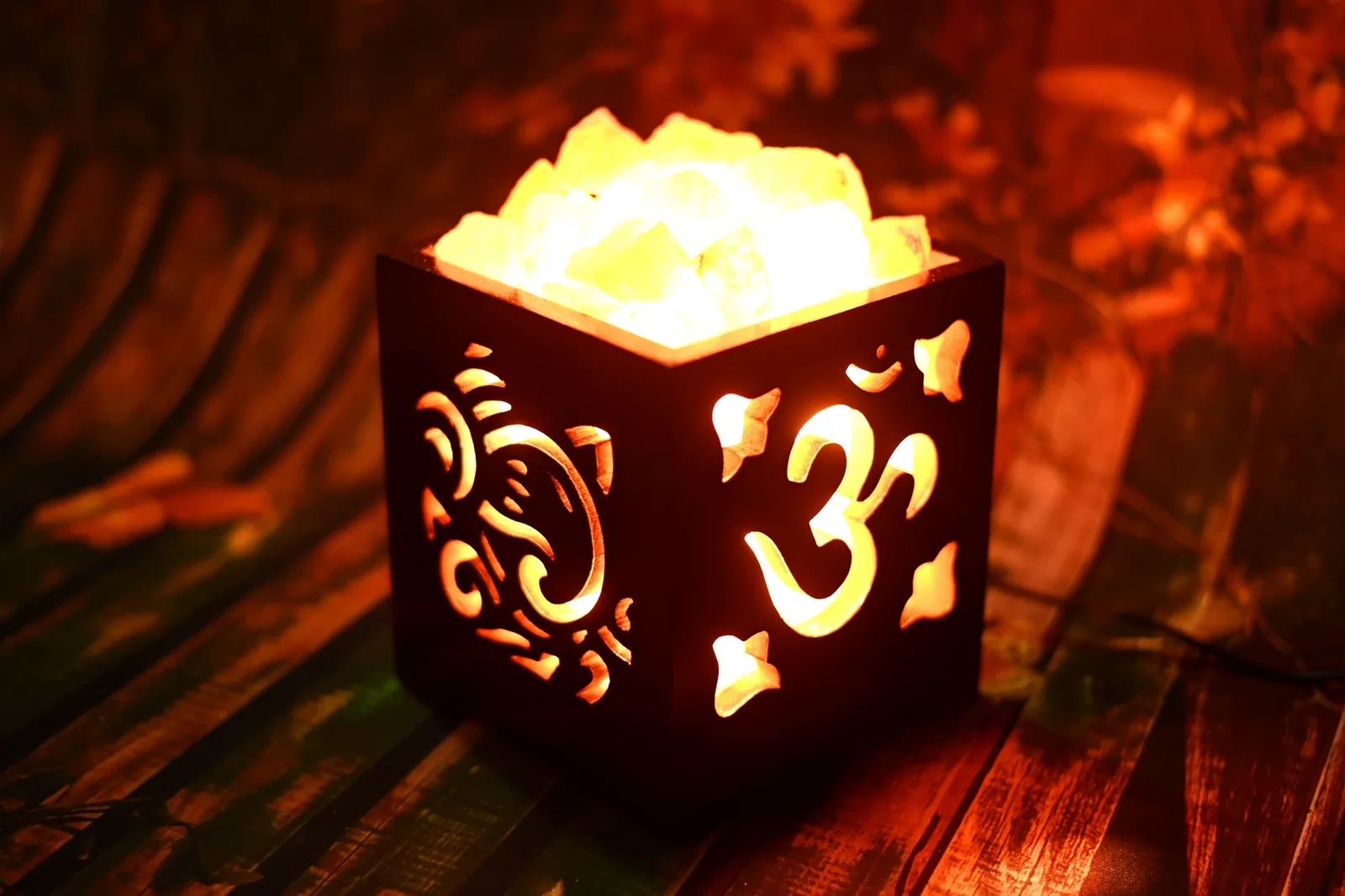 Glowing Ganesh and Om salt lamp on a wooden surface